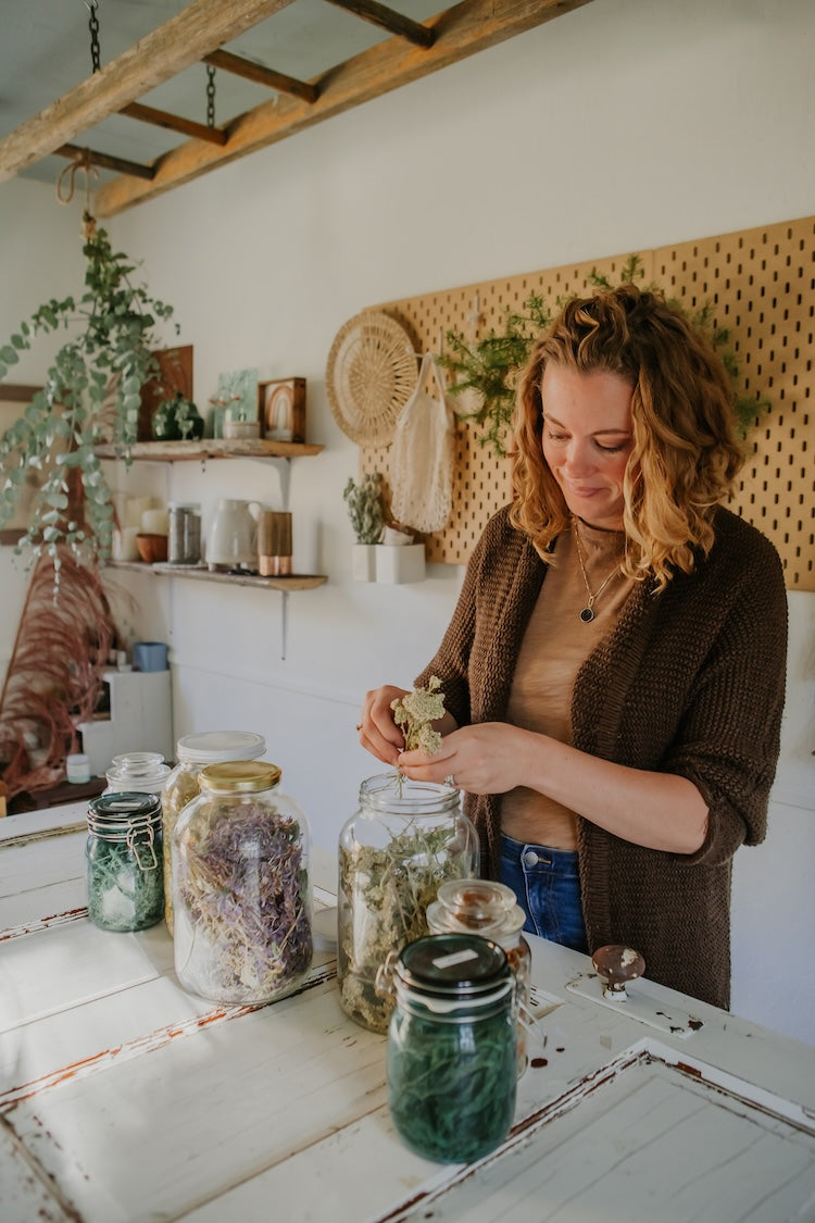 woman working with dried herbs in jars
